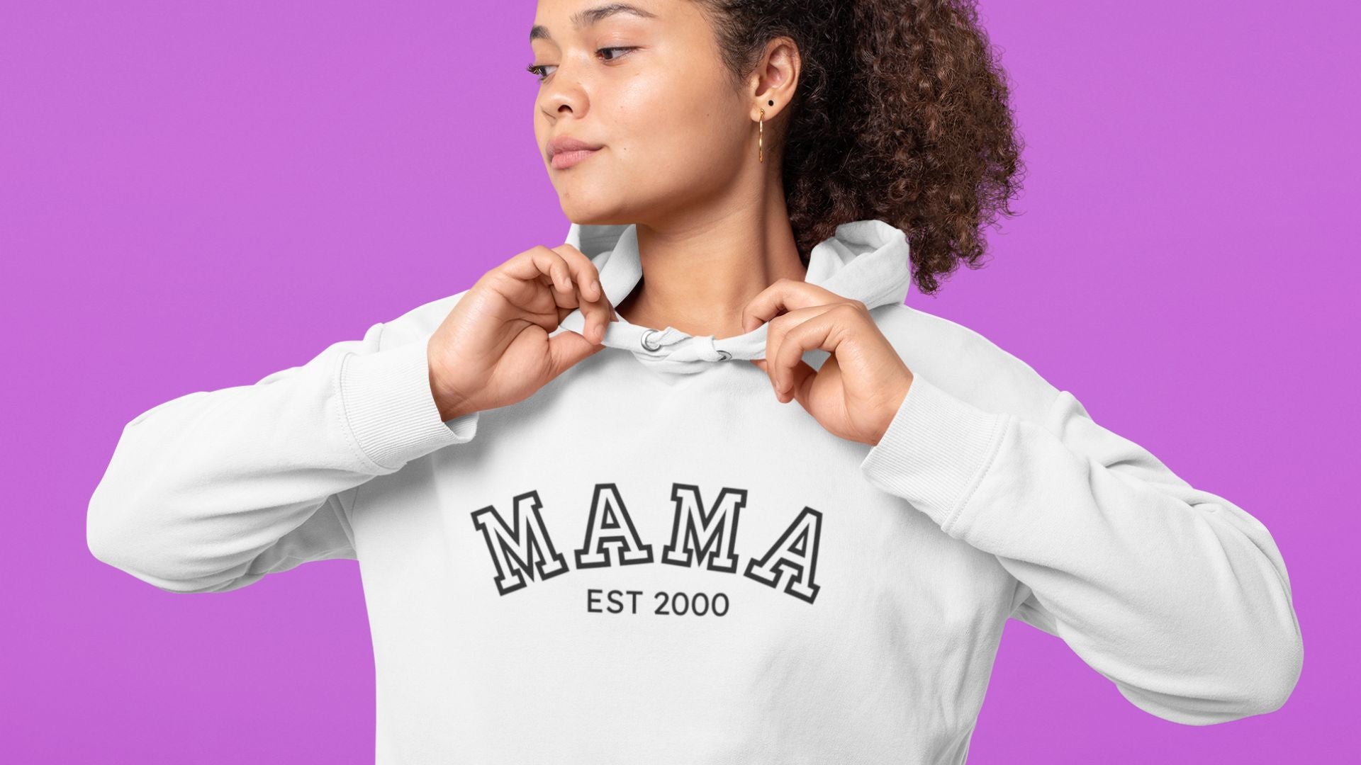 Stylish white hoodie with “MAMA EST 2000” text, modeled against a purple background—perfect cozy gift for moms or fashion-forward mamas.